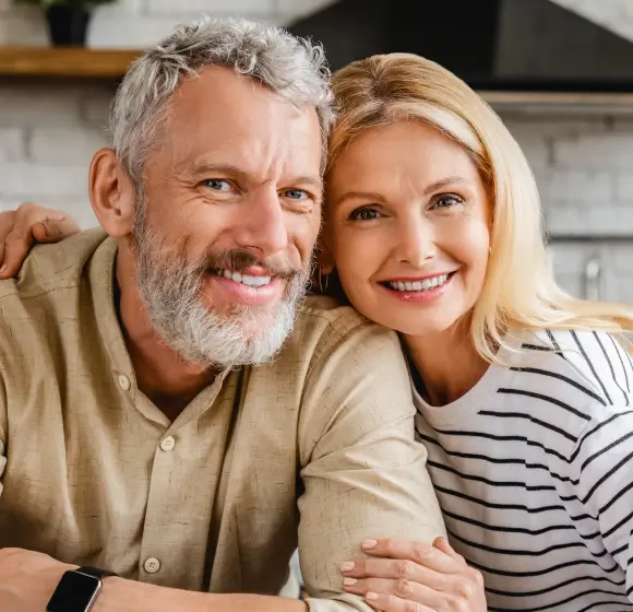 Happy mature couple smiling together, representing dental implant success and restored confidence.
