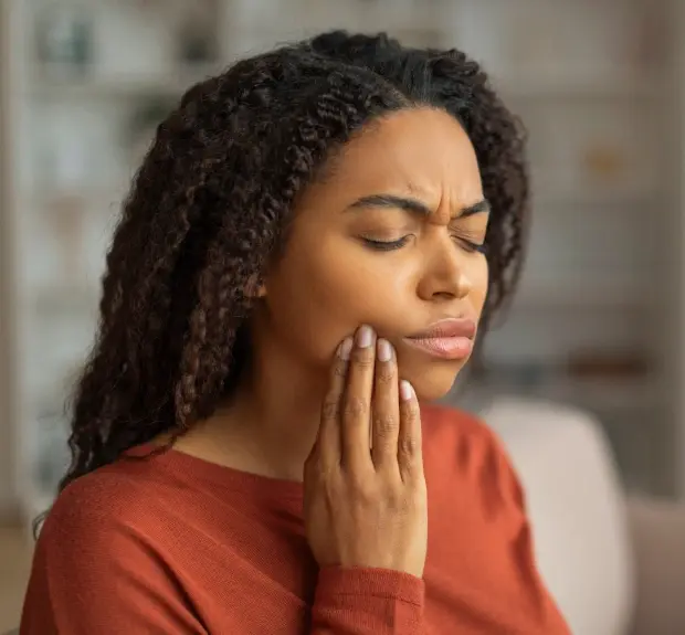 Woman with tooth pain holding her cheek in need of emergency dental care.