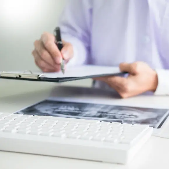 Dental professional reviewing insurance and financing options at desk with laptop.