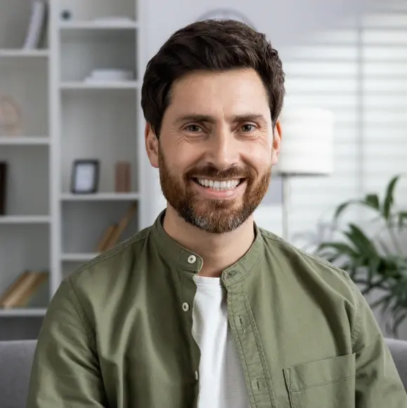 Smiling man in green shirt in modern dental office setting.